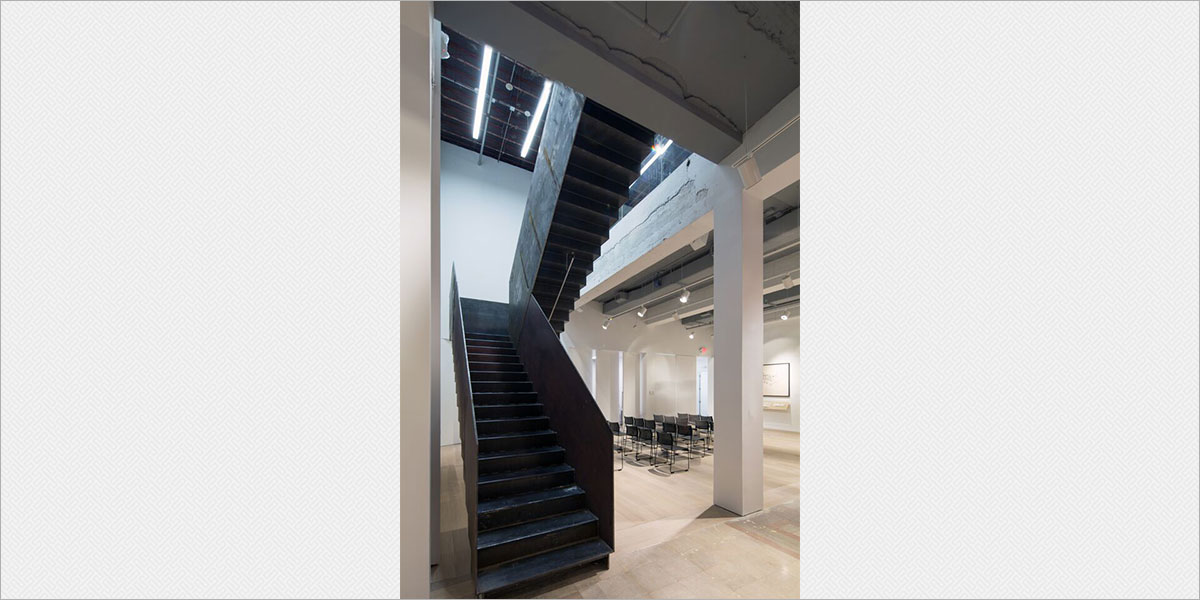 Focal Point Seem4 LED linear pendants illuminate the staircase and second level, and Lithonia Flatback track heads with LED lamps accent the walls of the presentation space.